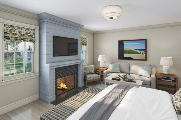 A cozy bedroom with a fireplace, TV, sofa, coffee table, and a large bed. Natural light comes in through the windows, and wall art is displayed.